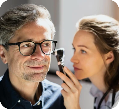 ENT specialist examining a male patient’s ear during an in-person consultation